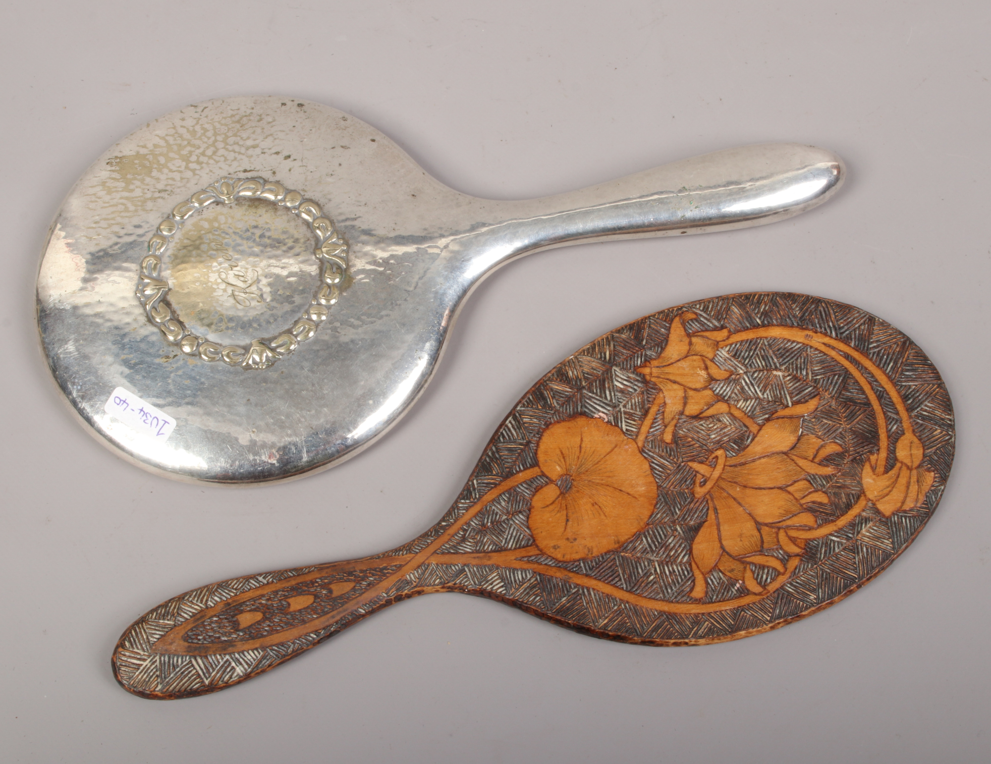 A Pokerwork hand mirror with floral decoration, along with a silver plate hand mirror.