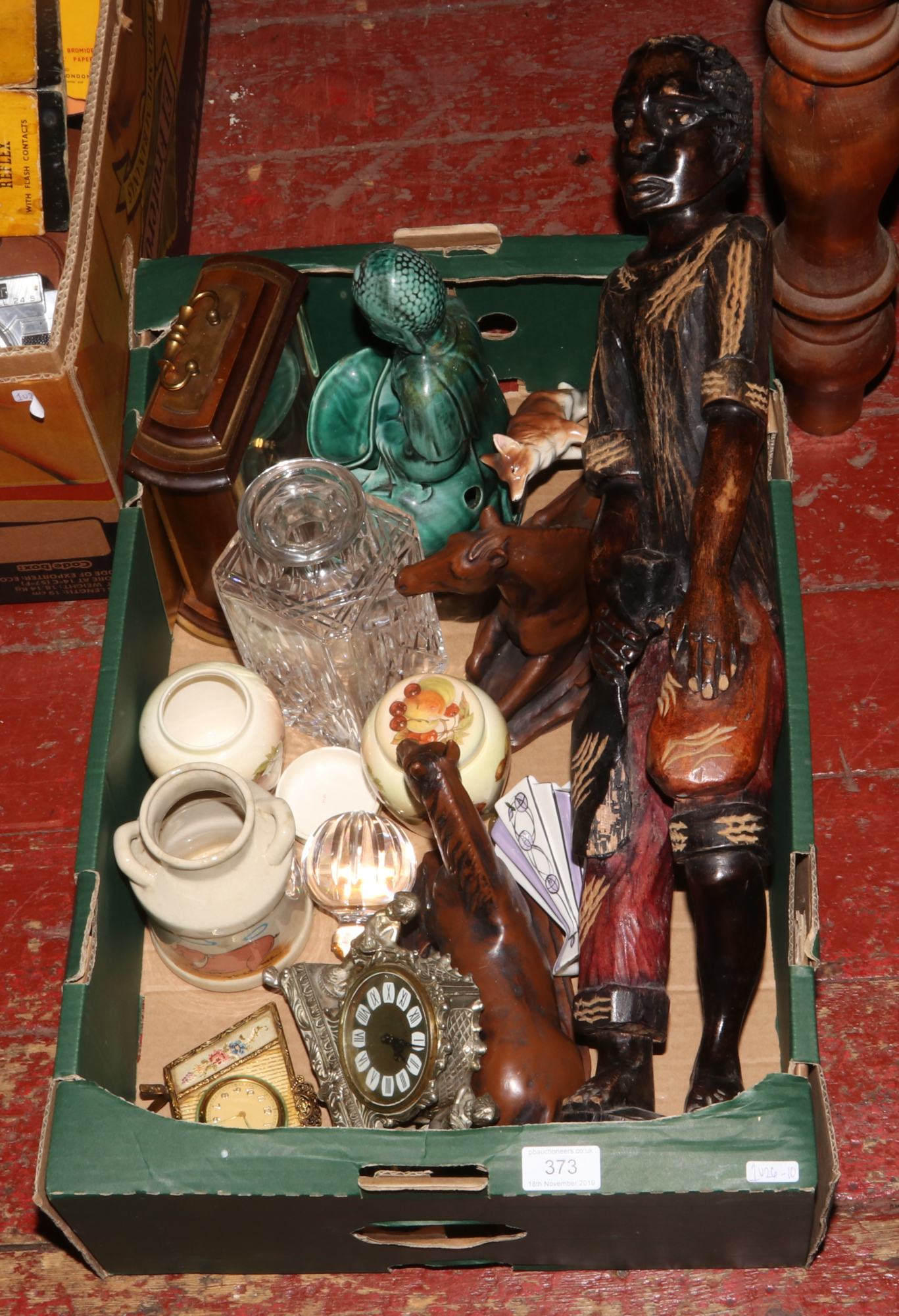 A box of miscellaneous including a carved hardwood figure of a man, composite models of horses,