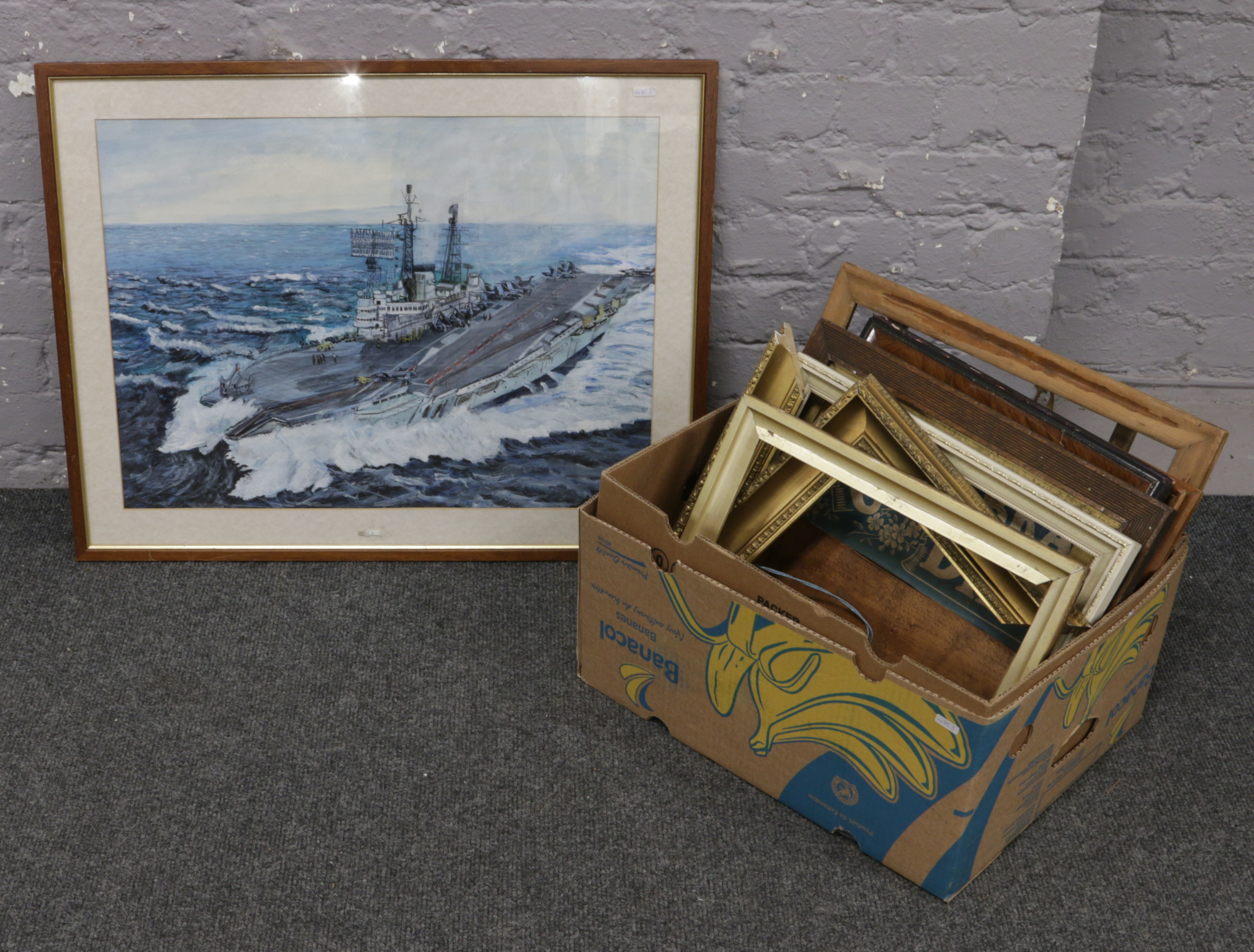 A box of pictures frames and a framed pastel study of a Royal Navy aircraft carrier.