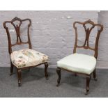 A pair of carved mahogany salon chairs with floral upholstery.