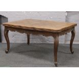 A French carved oak drawer leaf dining table raised on scrolled cabriole legs.