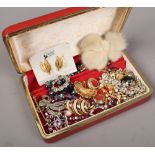 A red jewellery box containing vintage costume jewellery including 1950s beads and brooches,