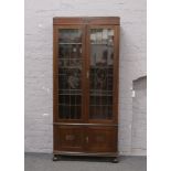 A George V carved oak bookcase with lead glazed doors, raised on turned bun feet, 86cm Wide x 32cm