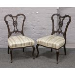 A pair of carved mahogany salon chairs on slender cabriole legs.