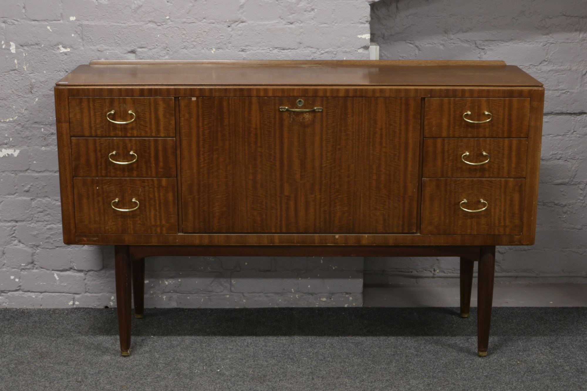 A mahogany sideboard with drop down centre raised on tapering supports.