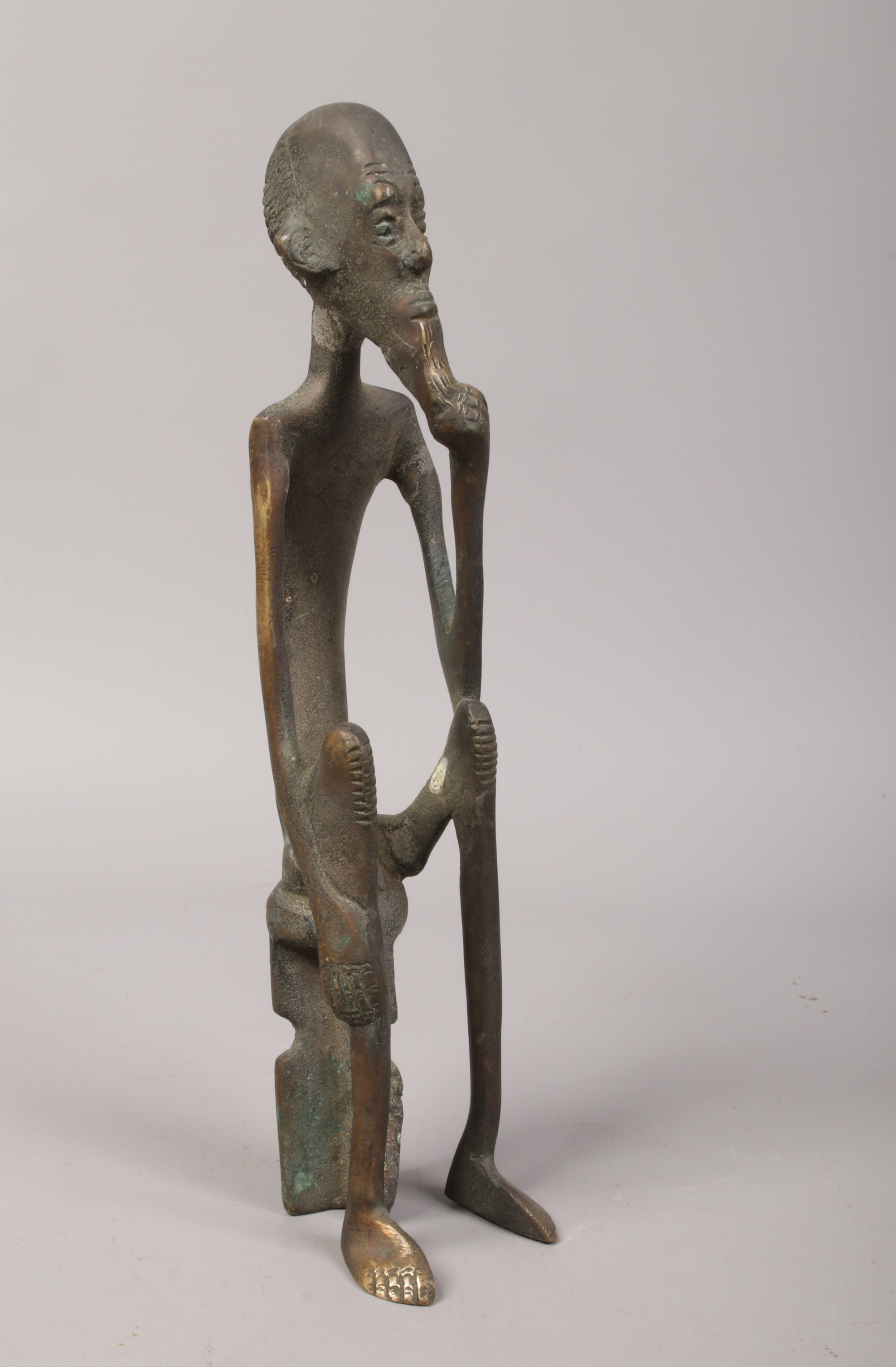 An African Berin style bronze figure of a tribesman seated on a stool.