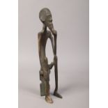 An African Berin style bronze figure of a tribesman seated on a stool.