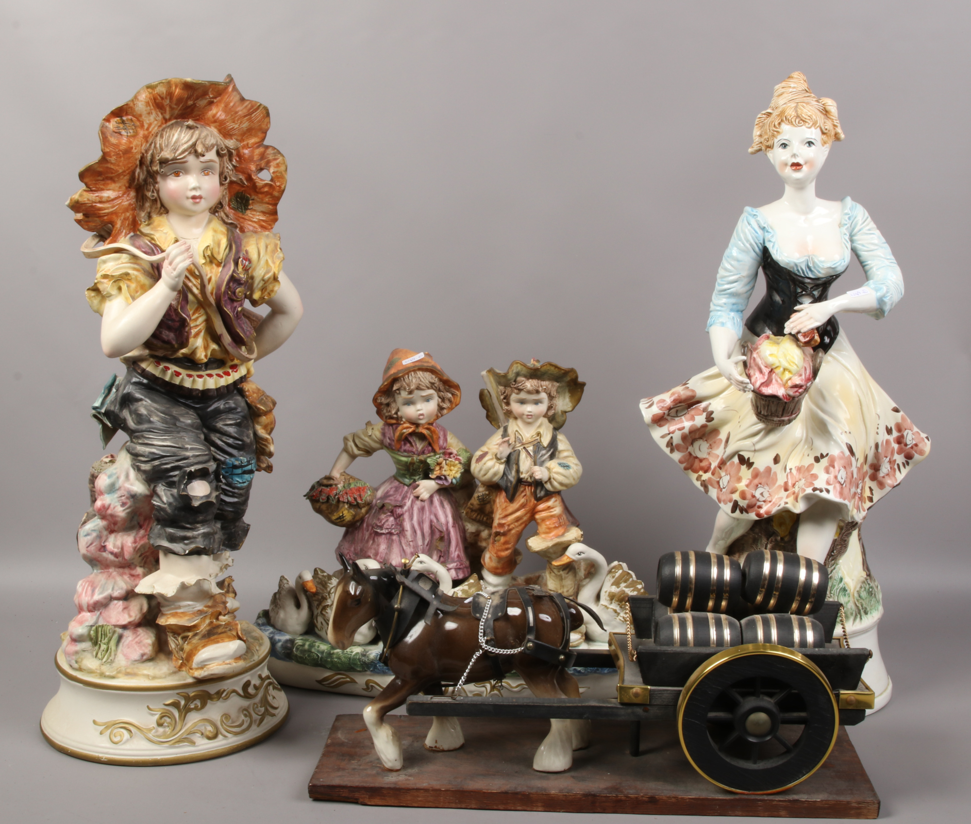 Two large Capodimonte figures, along with a similar figure group and a horse and dray.