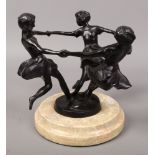 A Spelter bronze effect dancing girls figure group raised on a circular marble effect base.