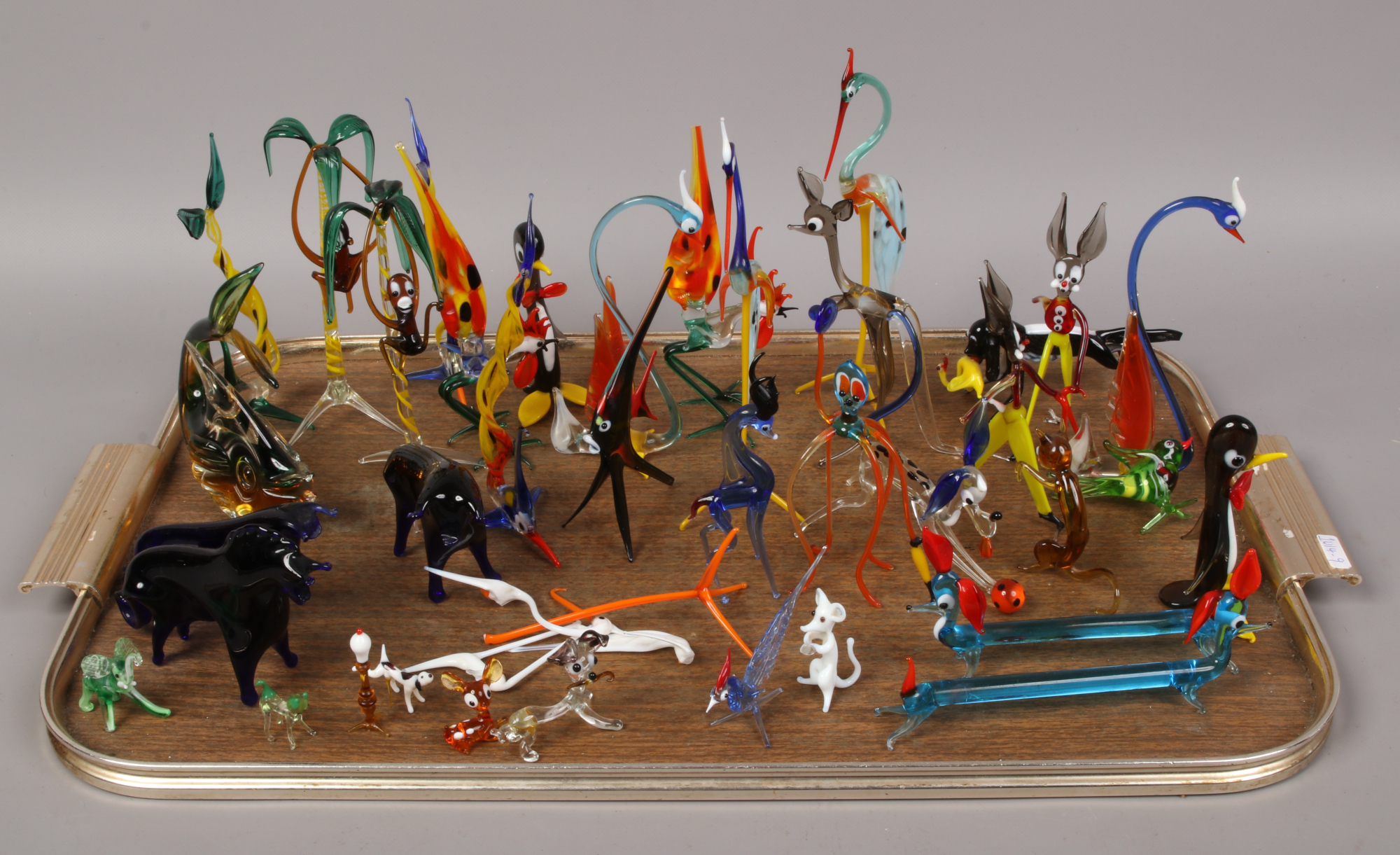 A tray of hand blown coloured glass models of animals, fish and birds.