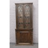 A carved and panelled oak lead glazed bookcase over a cupboard base, W 82cm x D 36cm x H 194cm.