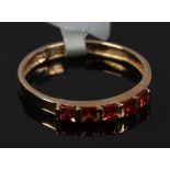 A 9ct gold dress ring with five Princess cut red / orange gemstones, size O.