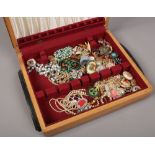 A wooden box of costume jewellery including brooches, simulated pearls, necklaces etc.