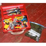 A red carry box of assorted Lego along with a bag green coloured Lego.