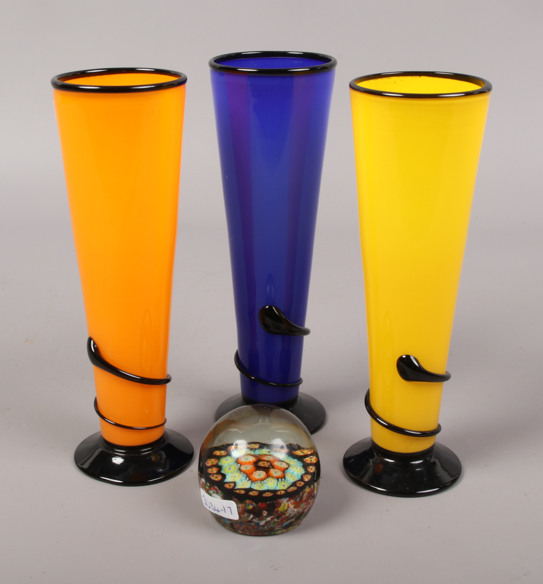 Three New Zealand colour art glass vases, along with a glass spilt cane paperweight.