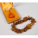 An amber pendant with flower petal inclusion on gold plated chain, along with a amber irregular bead