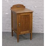 An Edwardian carved oak pot cupboard raised on tapering square cut legs.