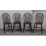 A set of four ebonised wheel back chairs.