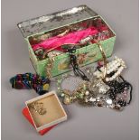 A tin of costume jewellery to include brooches, bangles, beads, necklaces etc.