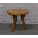 A pine cross section coffee table raised on three leg base.