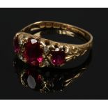 An Edwardian 18ct gold ring, set with three faceted red stone, boarded by diamonds, assayed