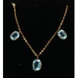 An early 20th century gold necklace with three rectangular cut blue stone drops.