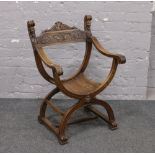 A carved hardwood X frame chair decorated with masks.Condition report intended as a guide only.