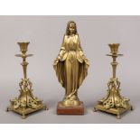 A pair of ornate brass candlesticks, along with a gilt spelter figure of the Virgin Mary.