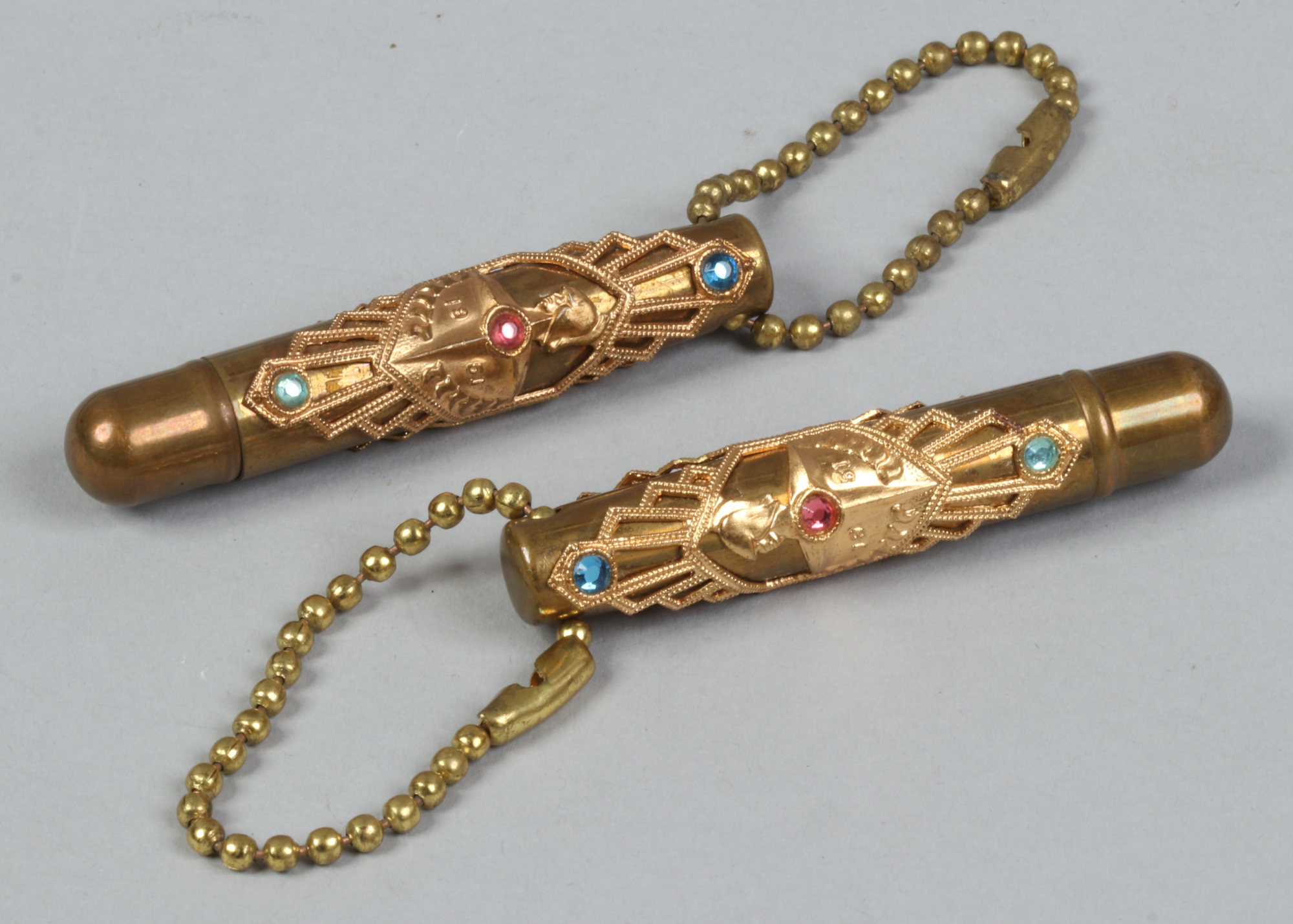 A pair of 1951 gilt cased miniature pens decorated with three coloured paste stones.