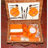 A wicker picnic hamper with contents of stainless steel cutlery and food storage containers.