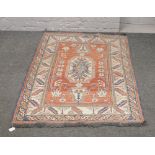 A red ground wool rug with geometric design and central medallion, 173 x 110cm.