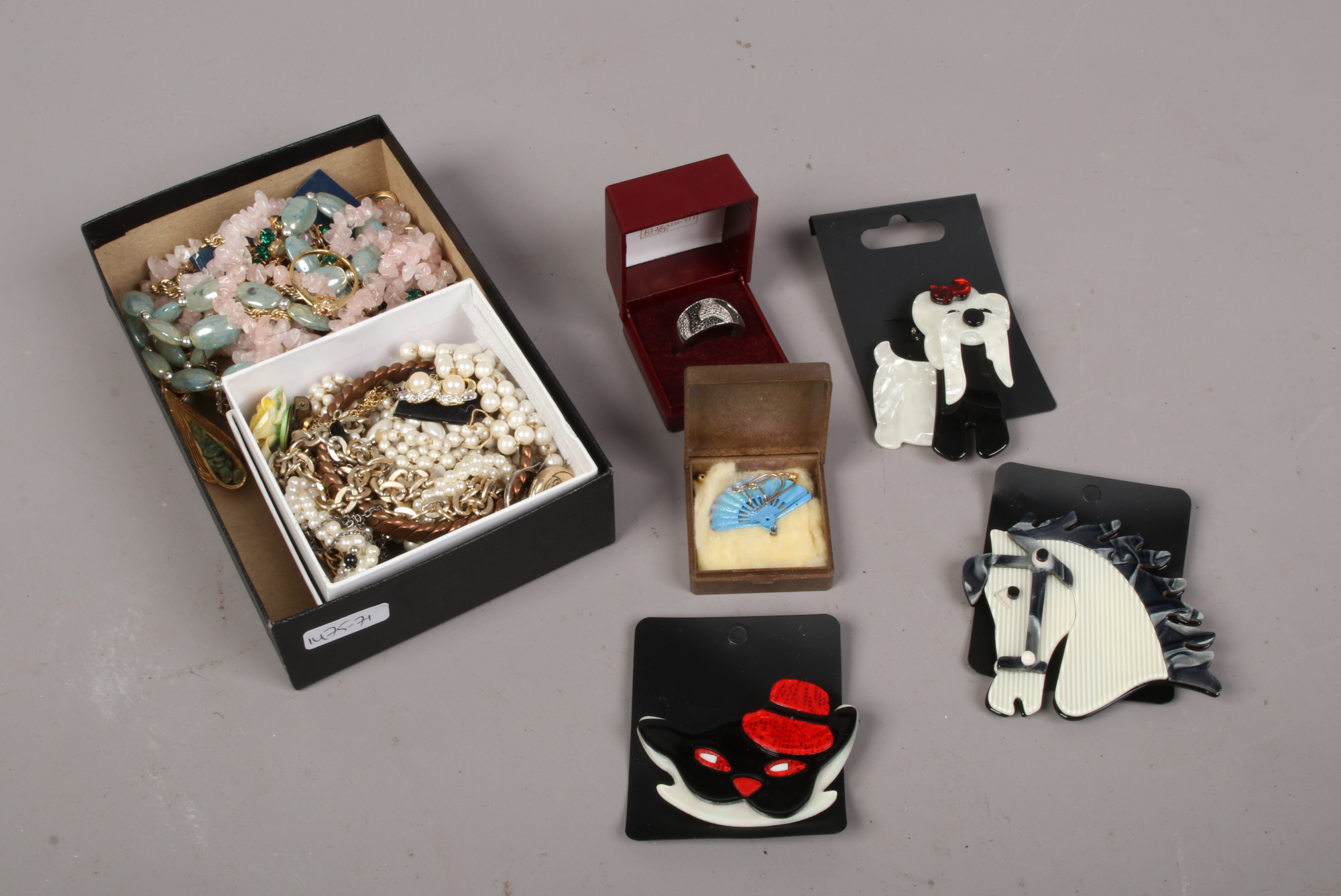 A box of costume jewellery including rose quartz necklace and brooches etc.