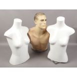 Three upper torso shop mannequins one on rotating base.