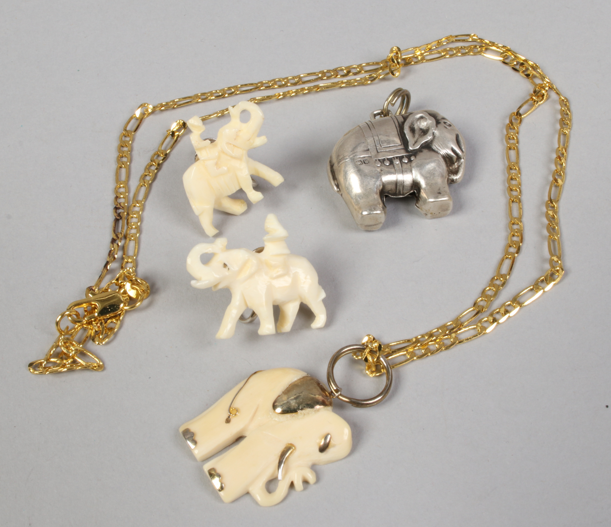 A pair of carved bone elephant earrings and similar pendants.