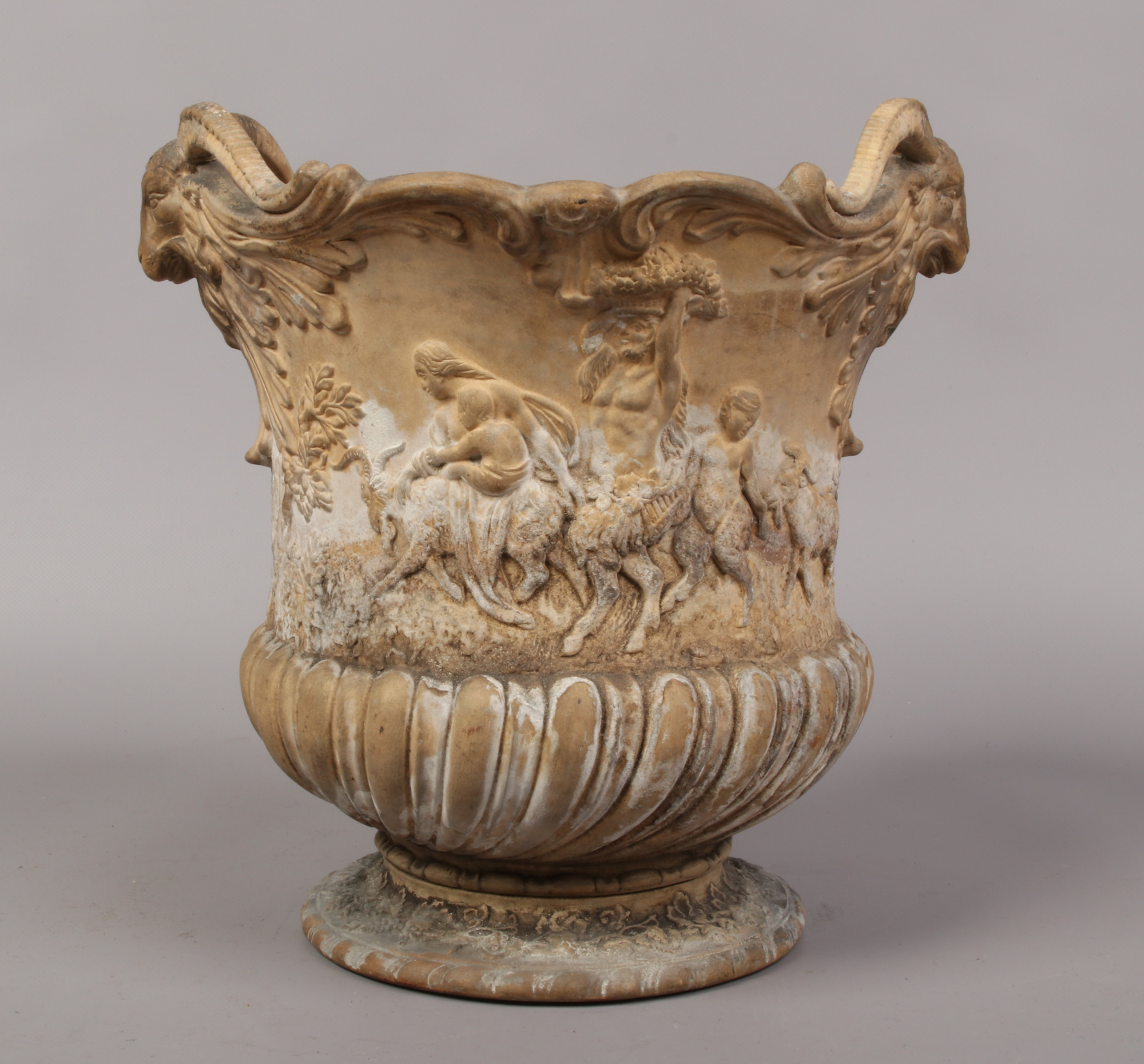 A Victorian earthenware urn moulded with twin ram masks, decorated with putti and fauns, impressed