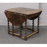 A carved oak drop leaf gateleg table, raised on barleytwist supports.