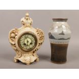 A pottery cased 8 day mantle clock with cylindrical movement, chiming on a bell along with a