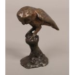 A cast bronze miniature model of a owl on naturalistic perch.