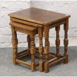 A nest of three oak occasional tables raised on turned supports.