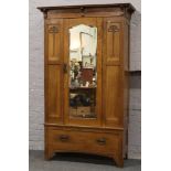 A mahogany Art Nouveau mirror front single door wardrobe raised over base drawer, 122cm wide x 206cm