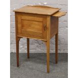 A light oak pot cupboard raised on tapering square supports.