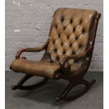 A deep buttoned brown leather mahogany scroll arm rocking chair.