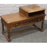 A carved oak telephone table raised on turned supports.