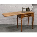 A walnut quarter veneered sewing table with built in Jones sewing machine, raised on tapering