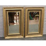 A pair of bevelled edge wall mirrors in cushion shaped gilt frames.