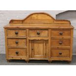 A Victorian carved pine sideboard of seven drawers with central cupboard and raised upstand raised