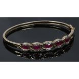 A 9ct gold openwork ruby and diamond bangle, 11.78 grams gross.