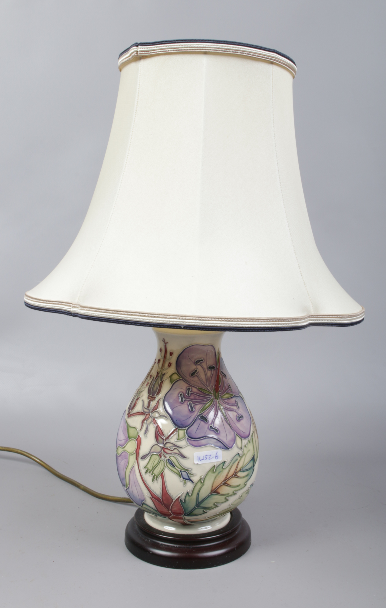 A Moorcroft pottery table lamp cream ground decorated with flowers and leaves.