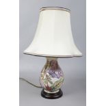 A Moorcroft pottery table lamp cream ground decorated with flowers and leaves.