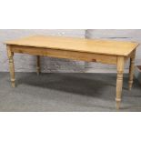 A Victorian pine kitchen table raised on turned supports.